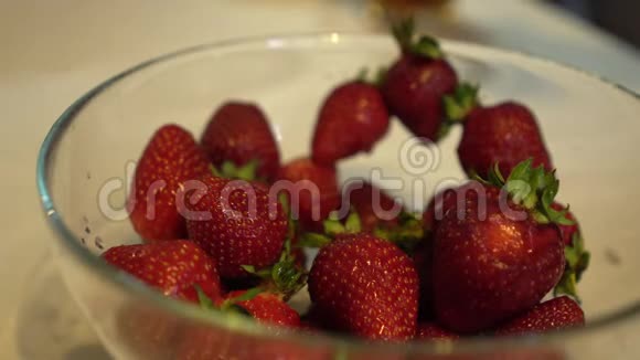 女性手从玻璃碗中取出新鲜成熟的草莓视频的预览图