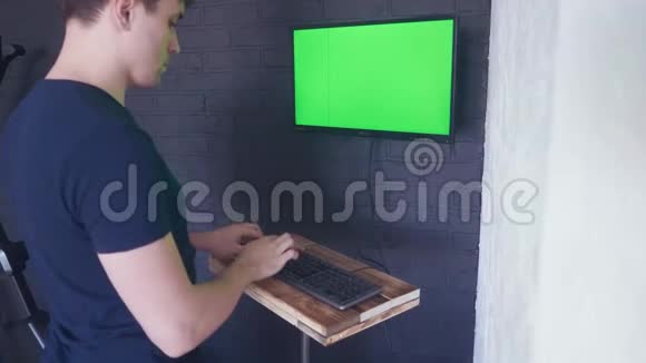 年轻人正在用一个绿色屏幕模拟电脑工作4K在键盘上慢慢打字视频的预览图