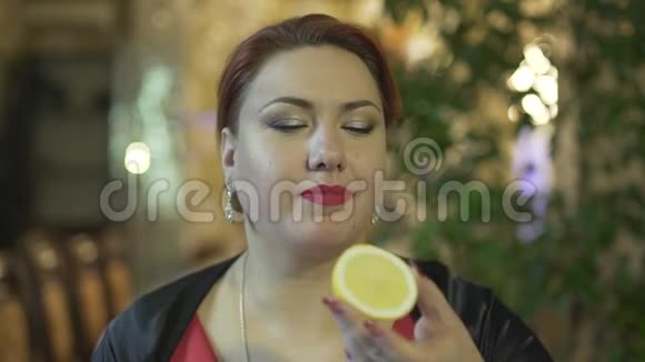 在高档餐厅里一位身材矮小的中年妇女正吃着咬人的柠檬边笑边喝水视频的预览图