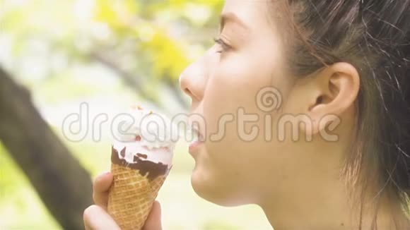 年轻女子在户外花园公园吃冰淇淋夏季阳光慢动作视频的预览图