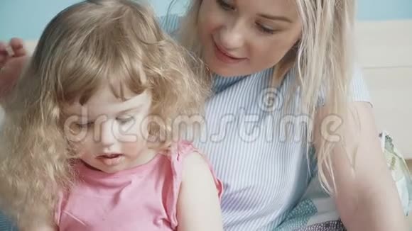 妈妈和她可爱的小女儿在智能手机上看视频视频的预览图