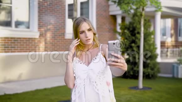 一个年轻性感的白衣女孩在夏日街独自拍照视频的预览图