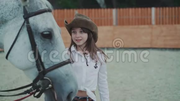 一个快乐的小女孩在这个地区抚摸漂亮的白马的肖像4K视频的预览图
