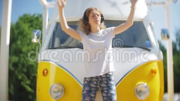 年轻女性在户外乘坐黄色车用智能手机耳机听音乐放松享受概念视频的预览图
