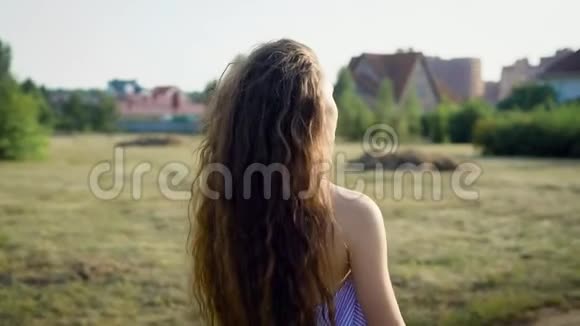 留着长发的女人在乡间的背景下在阳光下眺望视频的预览图