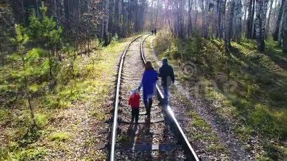 一个带着两个孩子在铁路上行走的小女孩秋天到户外散步视频的预览图