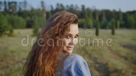 穿着牛仔服浓妆艳抹在自然背景下看着镜头的漂亮女孩的肖像视频的预览图