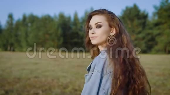 年轻时尚的女人长发浓妆艳抹在夏天的田野里摆姿势视频的预览图