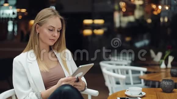 微笑的女人在商场里梳头看着平板电脑视频的预览图