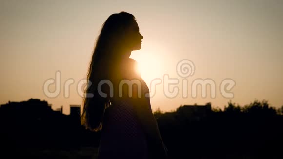 在明亮的夕阳下一个匿名的女人站在户外性感地看着远处视频的预览图