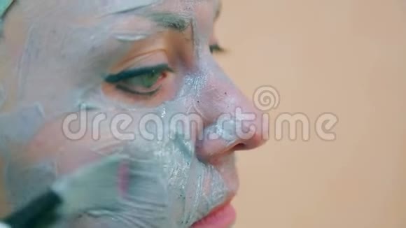 一个微笑的女人的脸头上有一条毛巾皮肤上有一刷蓝色的粘土视频的预览图