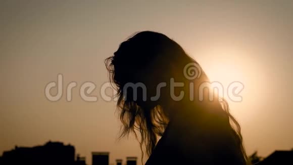 一个留着长发的匿名女子性感地摆姿势把头向后仰对着夕阳视频的预览图
