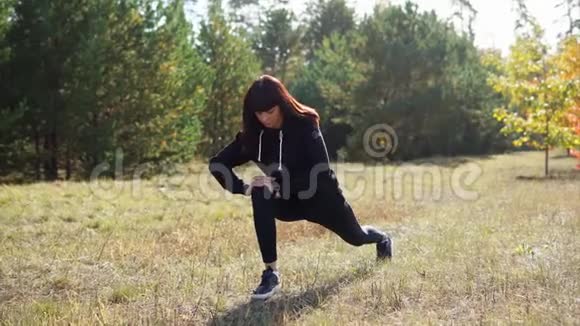 一位身穿运动服的妇女在慢跑穿过公园之前会使腿部肌肉变暖视频的预览图