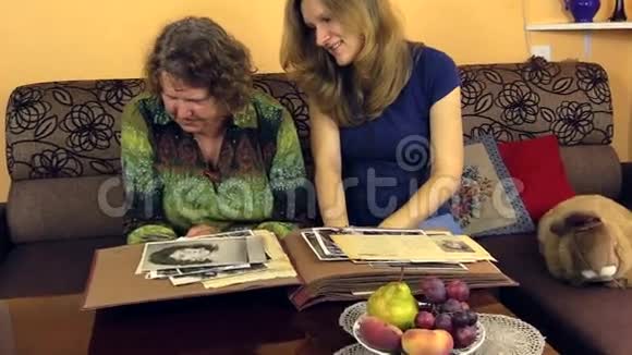 奶奶带着孙女看着老专辑里的照片视频的预览图