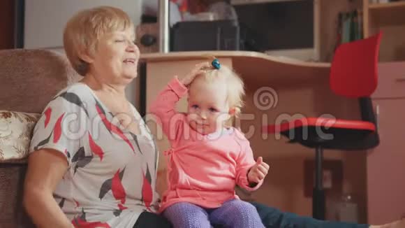 祖母带着她可爱的孙女微笑着说话玩耍梳头视频的预览图