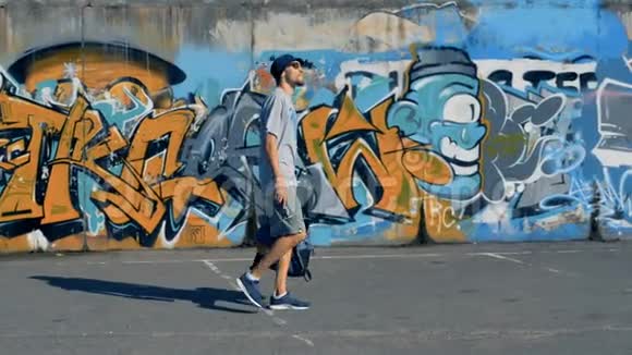 一位男性涂鸦艺术家沿着一面彩绘的墙走视频的预览图