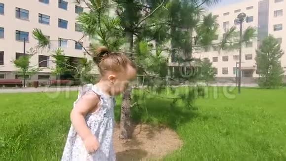 可爱的女婴在城市公园的草地上行走慢动作视频的预览图