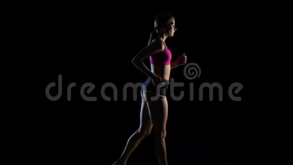 跑步女孩在黑色背景下过着健康的生活方式慢动作视频的预览图