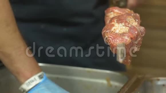 穿着蓝色手套的厨师把红肉腌制成串视频的预览图