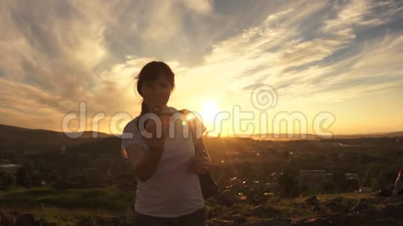 一个年轻的女人在一个夏天的晚上站在日落时扭动旋转器视频的预览图