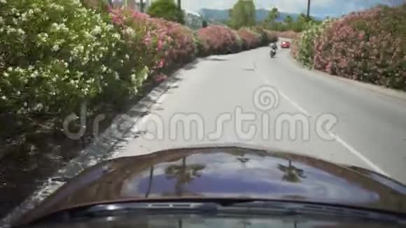 汽车沿着美丽的街道行驶周围是度假小镇的灌木丛视频的预览图