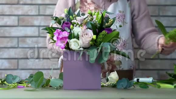 一个穿着围裙的花商用玫瑰风信子牡丹布鲁尼亚组成紫罗兰色的花视频的预览图