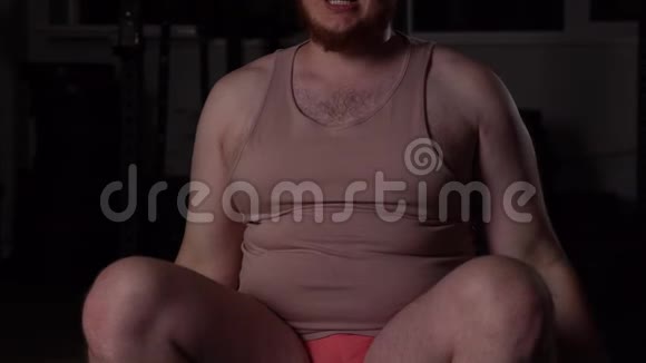 一个穿粉色衣服的超重胖子在健身房里用哑铃和健身球健身视频的预览图