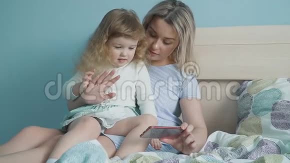 妈妈和她可爱的小女儿在智能手机上看视频视频的预览图
