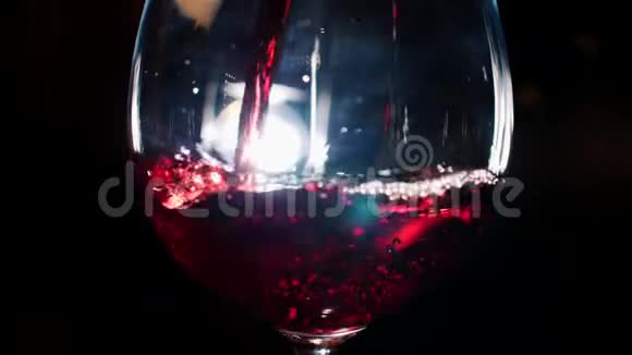 在黑暗中背景上有白光用红色的起泡葡萄酒浇注玻璃库存录像观点视频的预览图