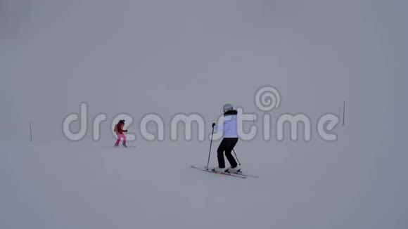 冬天两名女滑雪者在浓雾中下山滑雪视频的预览图