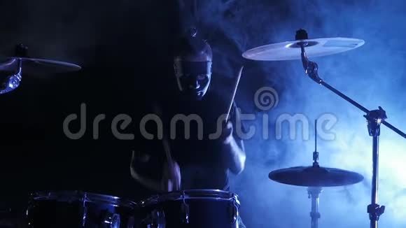 面具鼓手在舞台上演奏架子鼓以慢动作射击音乐视频朋克重金属或摇滚团体视频的预览图