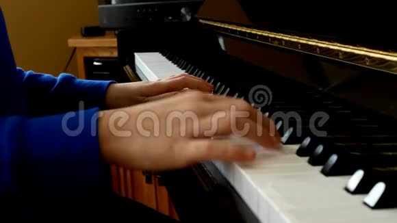 靠近年轻的手和手指的侧视在一架直立发亮的黑色钢琴的琴键上演奏一首歌视频的预览图