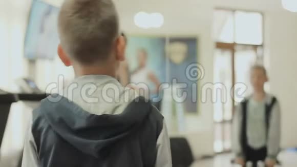 男孩把面前的哑铃靠在健身房的镜子上视频的预览图
