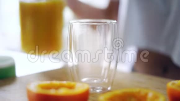 女人把橙汁从玻璃瓶里倒入玻璃杯里关上玻璃视频的预览图