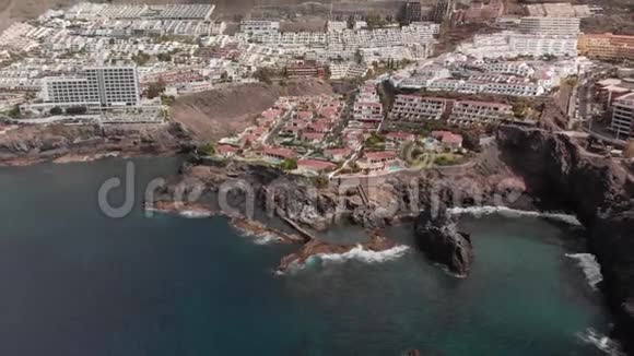 空中射击山度假小镇内有许多酒店棕榈树等植被蓝色的海洋和海浪拍打着视频的预览图