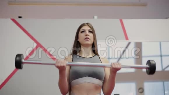 非常漂亮的女人在健身房用杠铃训练二头肌视频的预览图