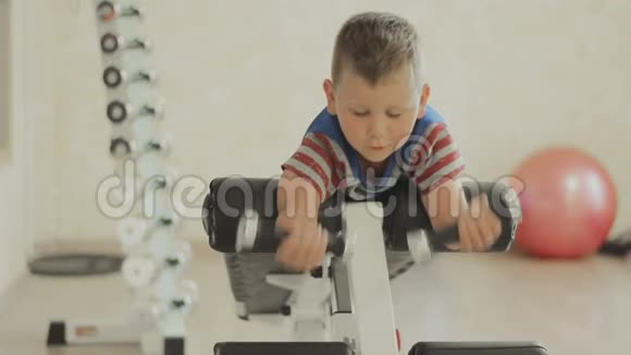 小男孩在做肱二头肌重量哑铃运动视频的预览图