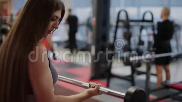 非常漂亮的女人在健身房用杠铃训练二头肌视频的预览图