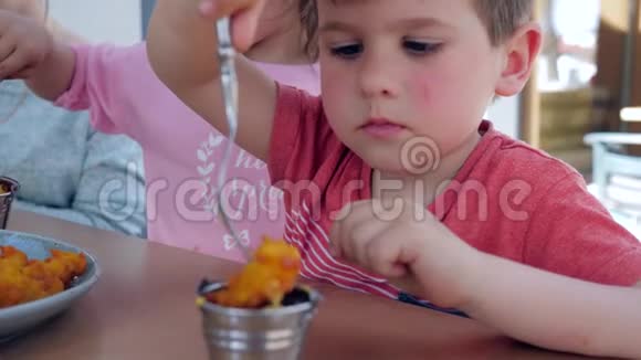 男孩和女孩正在餐馆吃一顿开胃的晚餐男孩子吃的是带酱汁的炸鸡块叉视频的预览图