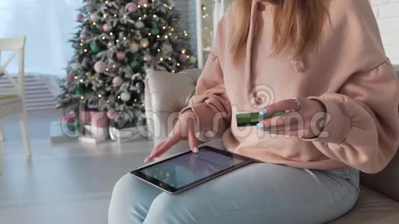 女人坐在沙发上通过在线输入信用卡信息用平板电脑在网上购物视频的预览图