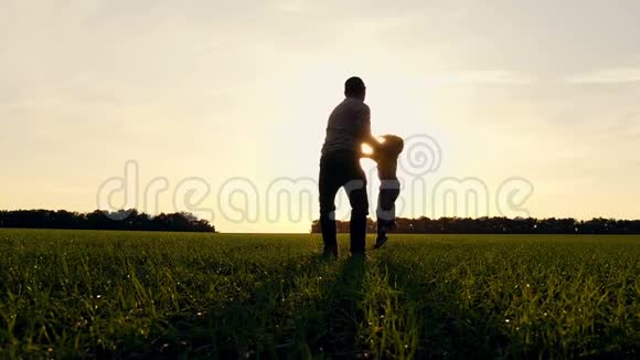日落时分快乐的父子在公园里玩大自然父亲牵着他的儿子的手和他一起转身慢慢视频的预览图