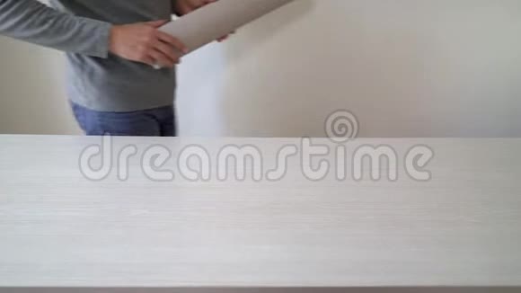 手工工人准备新的壁纸辊以便在室内桌面上做标记视频的预览图