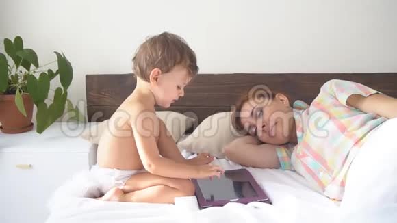 男孩用互联网平板电脑母亲睡觉视频的预览图