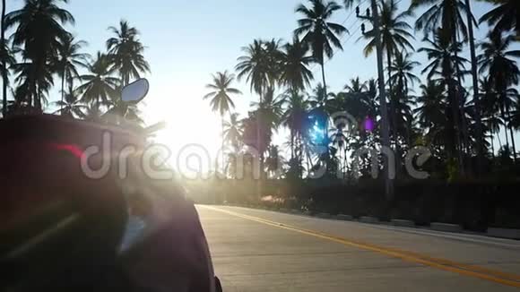 摩托车停在棕榈树之间的热带阳光大道上慢动作1920x1080视频的预览图