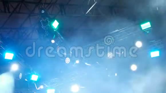 音乐会灯光和烟雾在雨中舞台上明亮的黄色和蓝色的探照灯模糊的背景视频的预览图