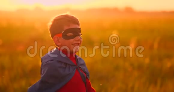 一个戴着面具的男孩和一个超级英雄在日落时在田野里的斗篷视频的预览图
