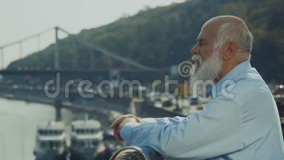 头发花白留着胡须的老人在河边放松欣赏风景视频的预览图