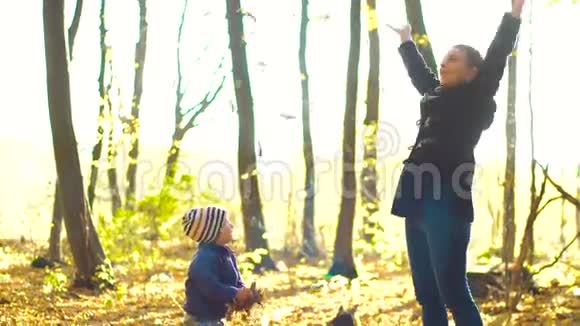 快乐的小男孩在森林里玩秋天的落叶视频的预览图