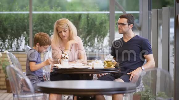 妈妈看着男孩在餐厅的露台上一起吃饭视频的预览图