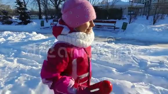 侧视小女孩在冬季公园跑步冬日阳光明媚视频的预览图